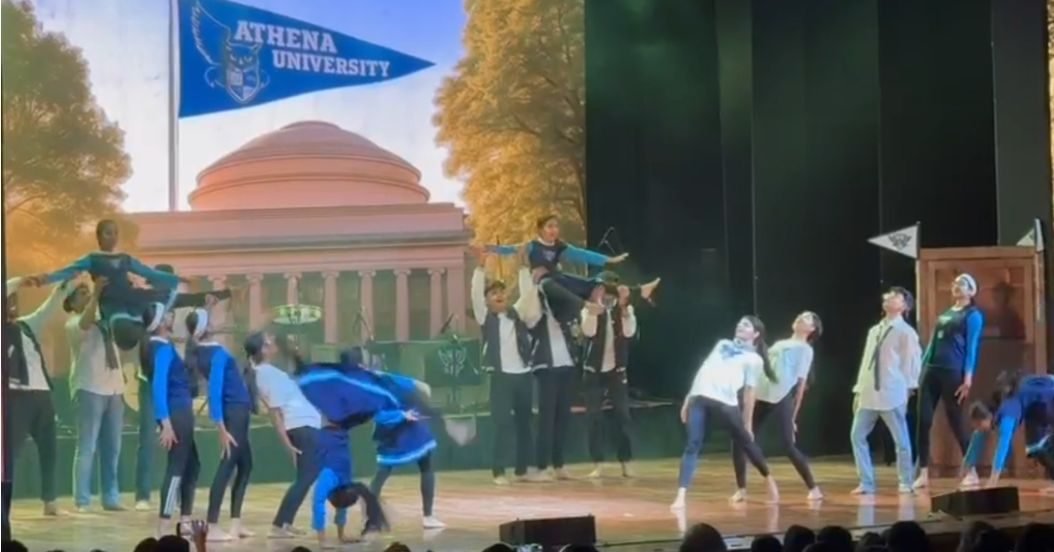 Dancers on stage in front of a projected university campus backdrop