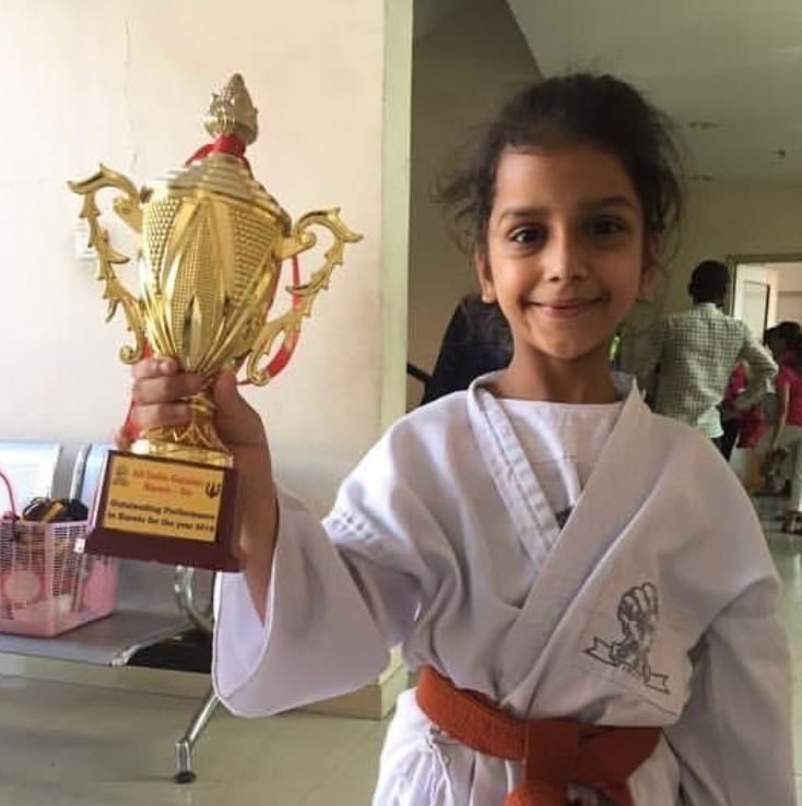 A young Ariana holding a large gold trophy